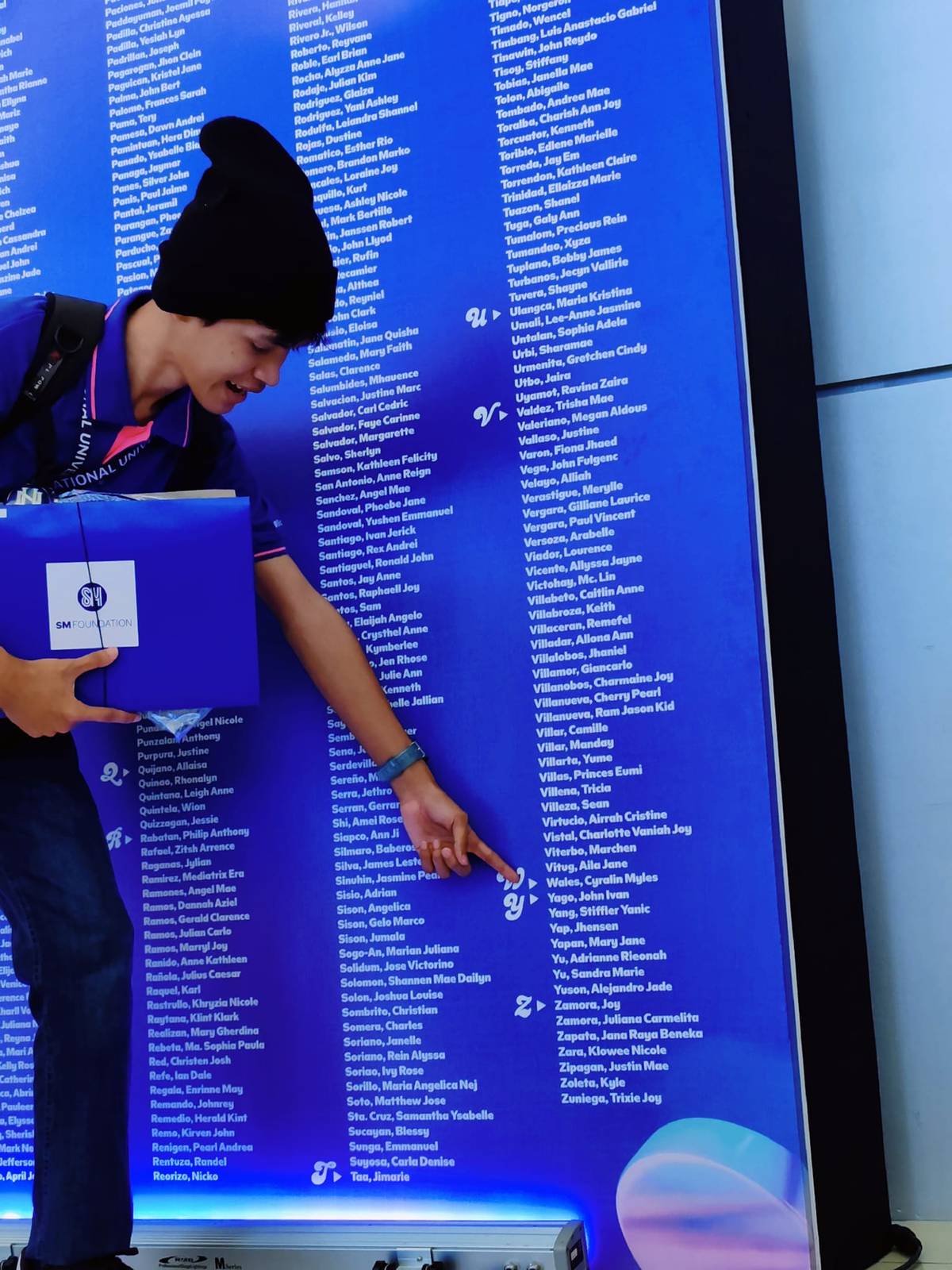 JOHN Ivan Yago points to his name on the roster of the latest batch of SM scholars at the SMX Convention Center in Pasay City.